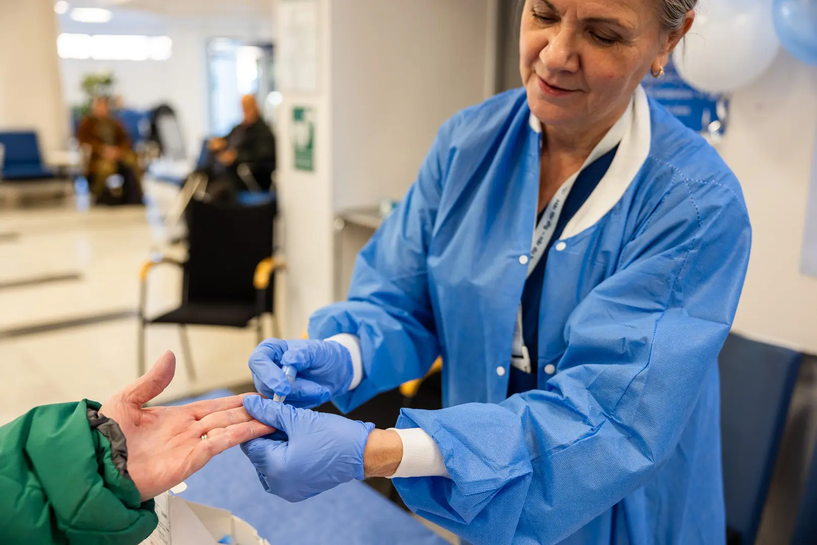 En diabetessjuksköterska testar blodsockret på en patient. 